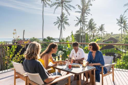 Illumera Lifestyle and Experiences Adults relaxing on a resort terrace surrounded by greenery